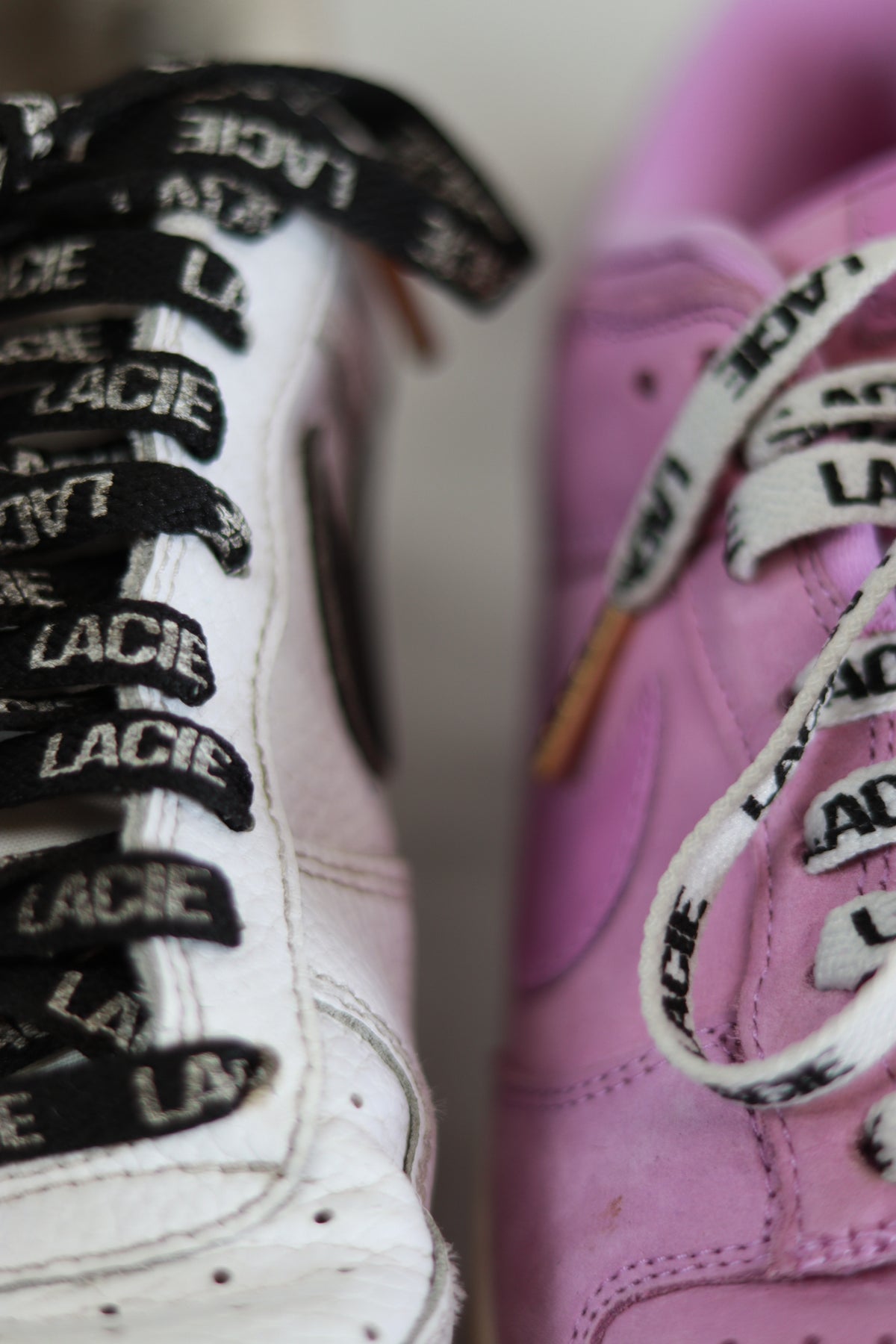 Close-up of LACIE All-Over Laces in black on white sneakers and white on pink sneakers
