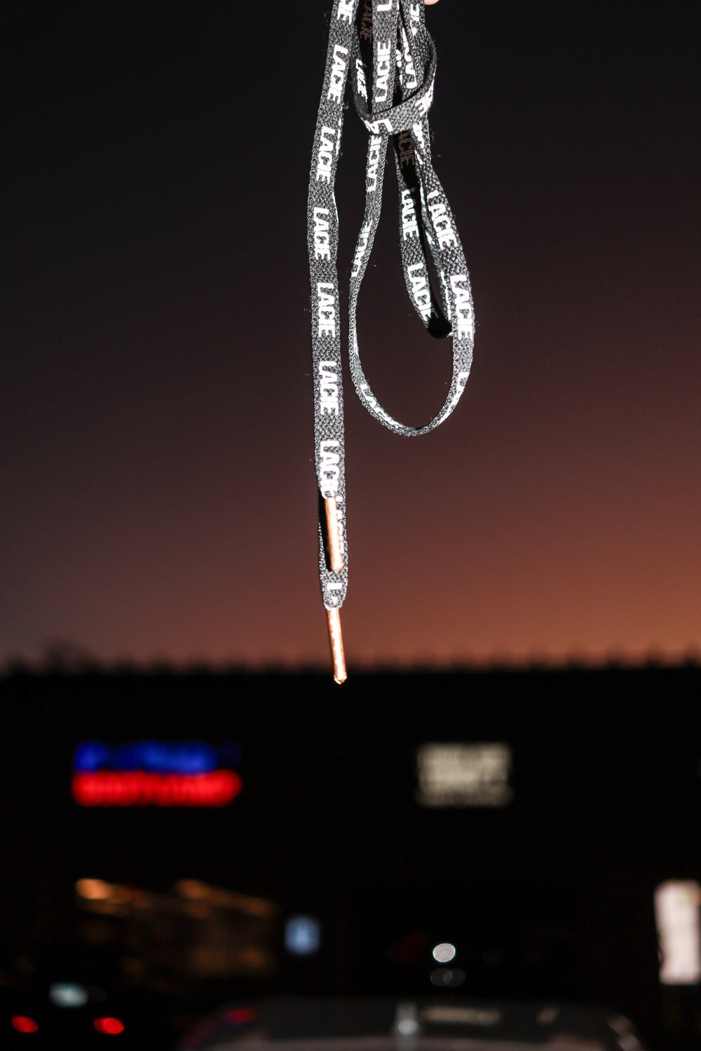A LACIE All-Over Lace held up against a dusk sky over neon signs