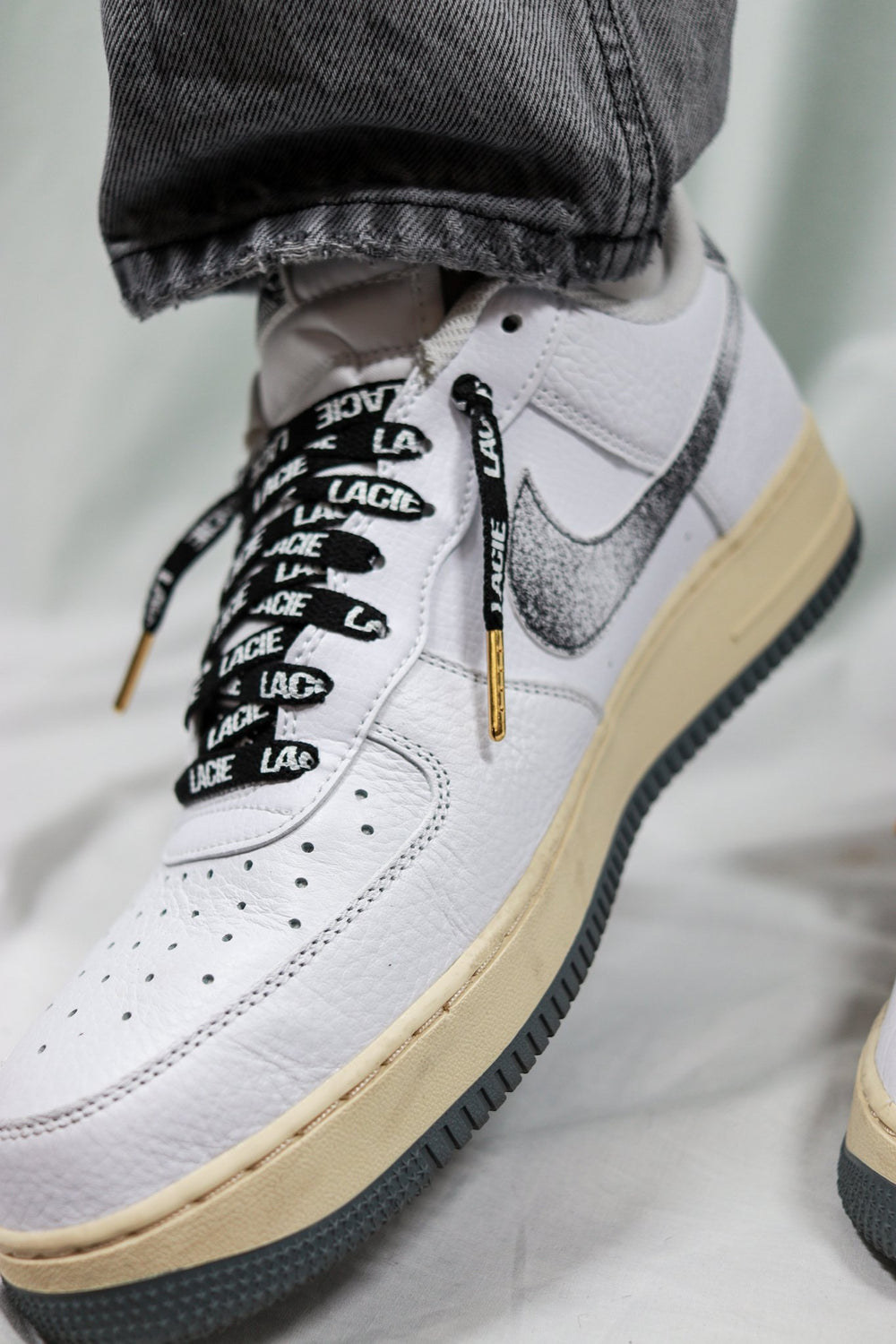 White AF1 laced with black LACIE All-Over Laces and gold aglets