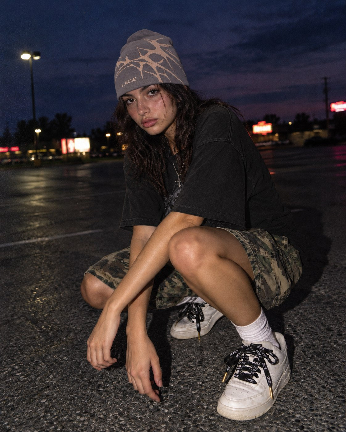 Crouched in a parking lot at blue hour wearing the LACIE Thorn Beanie and black LACIE laces