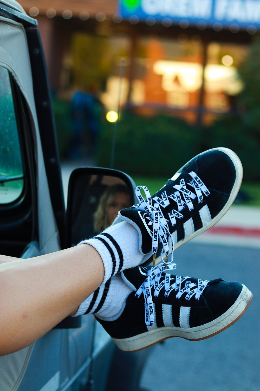 Feet out a car window in sneakers laced with LACIE laces